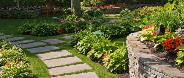 garden with a stone path, colorful plants and a decorative stone wall